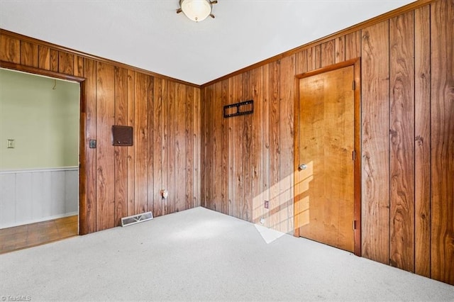 carpeted empty room featuring wooden walls