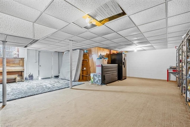 basement featuring stainless steel refrigerator, a drop ceiling, and carpet