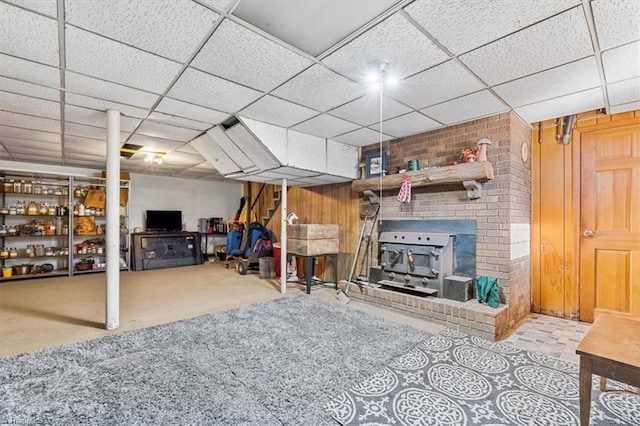 basement with a paneled ceiling and a wood stove