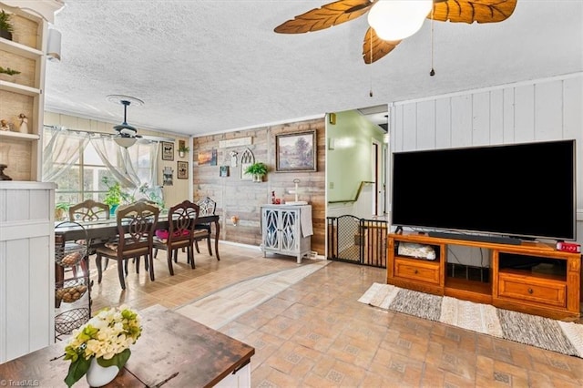 living room with a textured ceiling, ceiling fan, and wooden walls