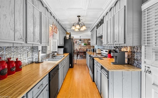 kitchen featuring an inviting chandelier, sink, hanging light fixtures, light wood-type flooring, and stainless steel appliances