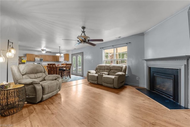 119 Tadworth Ct, Mebane, NC 27302 - living room featuring light wood-type flooring, a ceiling fan, a fireplace with flush hearth, and crown molding