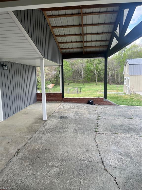 view of car parking featuring an attached carport and a storage unit