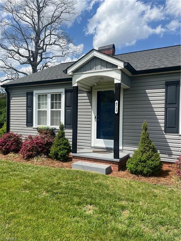view of front of property with a shingled roof and a front lawn
