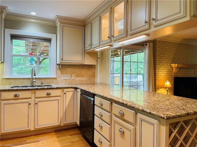 kitchen featuring a sink, cream cabinetry, light wood finished floors, black dishwasher, and a peninsula