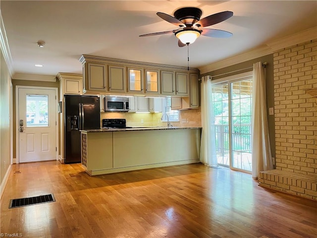 kitchen featuring stainless steel microwave, black fridge with ice dispenser, ornamental molding, stove, and a peninsula