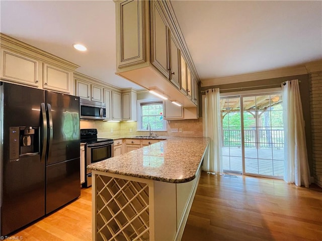 kitchen featuring stainless steel microwave, a sink, black fridge with ice dispenser, electric range oven, and a peninsula