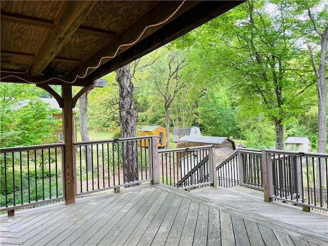 wooden terrace featuring a storage shed and an outdoor structure