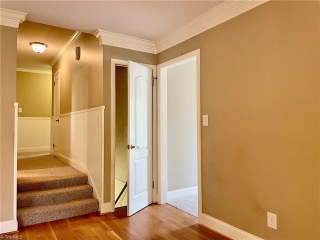 stairs with ornamental molding, wood finished floors, and baseboards
