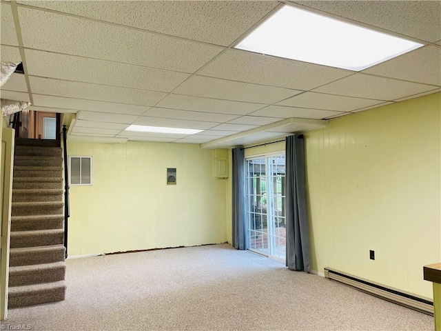 basement featuring baseboard heating, stairway, carpet floors, and a paneled ceiling