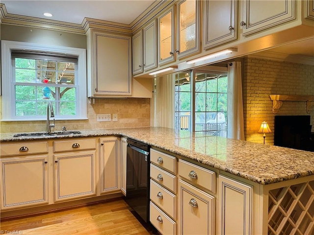 kitchen featuring cream cabinets, ornamental molding, dishwasher, a sink, and a peninsula