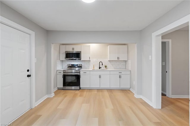 kitchen featuring appliances with stainless steel finishes, sink, decorative backsplash, and white cabinets