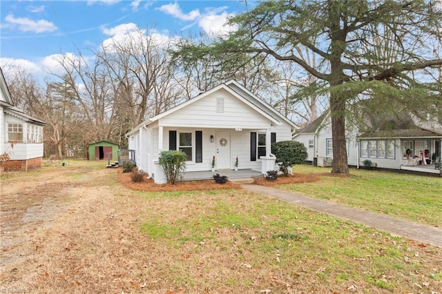 view of front of property featuring a front yard, covered porch, and a shed