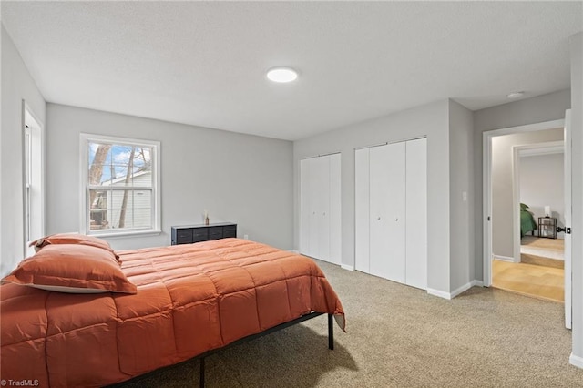 bedroom featuring two closets and light colored carpet