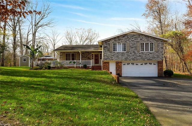 tri-level home with a garage, covered porch, a shed, and a front lawn