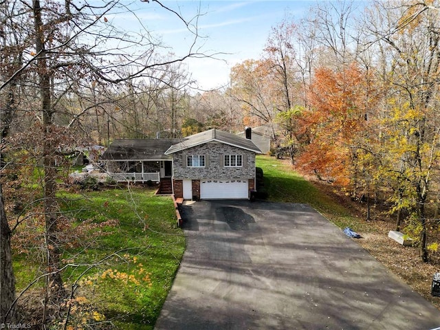 view of front of property with covered porch, a garage, and a front lawn