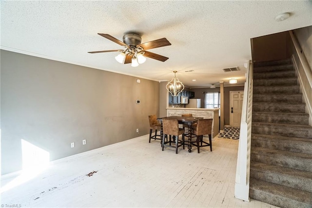 dining space featuring crown molding, ceiling fan with notable chandelier, and a textured ceiling