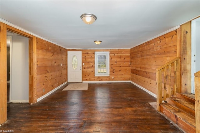 entrance foyer with dark hardwood / wood-style flooring, wood walls, and ornamental molding