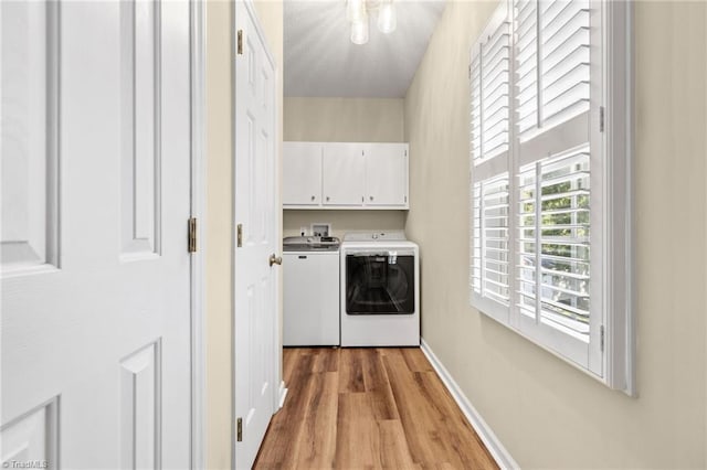 laundry area featuring cabinets, light wood-type flooring, and washing machine and dryer