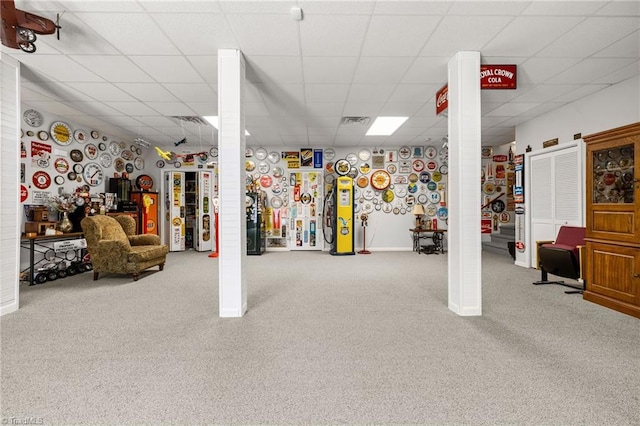 basement featuring a paneled ceiling and carpet flooring