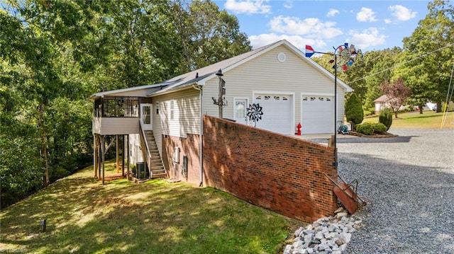 view of side of home featuring a garage, a lawn, and central AC