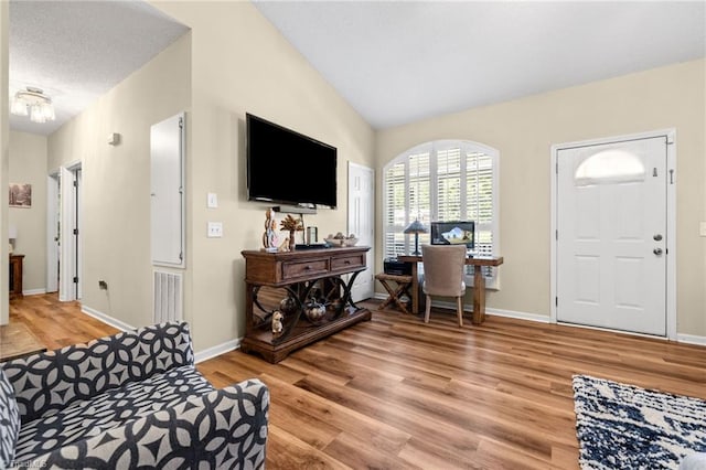 living room with a textured ceiling, light wood-type flooring, and lofted ceiling