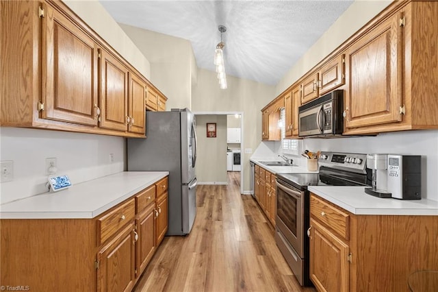 kitchen with pendant lighting, light wood-type flooring, sink, vaulted ceiling, and stainless steel appliances