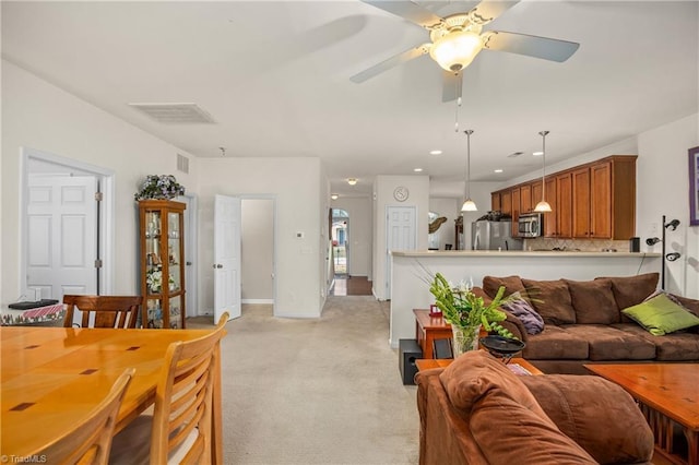 living room featuring recessed lighting, a ceiling fan, visible vents, baseboards, and light colored carpet
