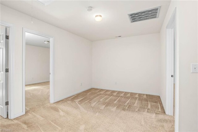 unfurnished room with attic access, visible vents, light carpet, and baseboards