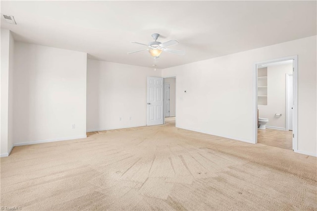 unfurnished room with visible vents, a ceiling fan, baseboards, and light carpet