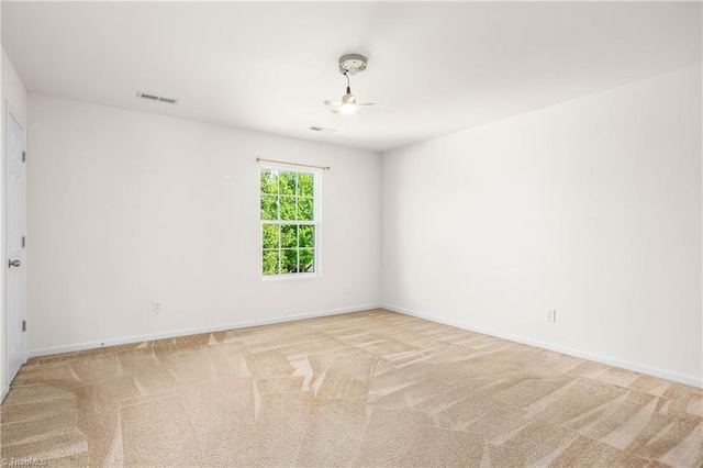 spare room featuring baseboards, visible vents, and light carpet