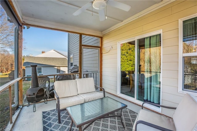 sunroom featuring outdoor lounge area, a ceiling fan, and a wood stove