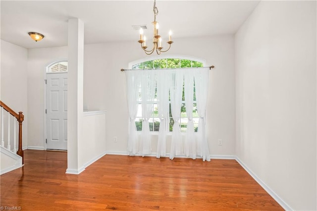 unfurnished dining area featuring a chandelier, visible vents, baseboards, wood finished floors, and stairs