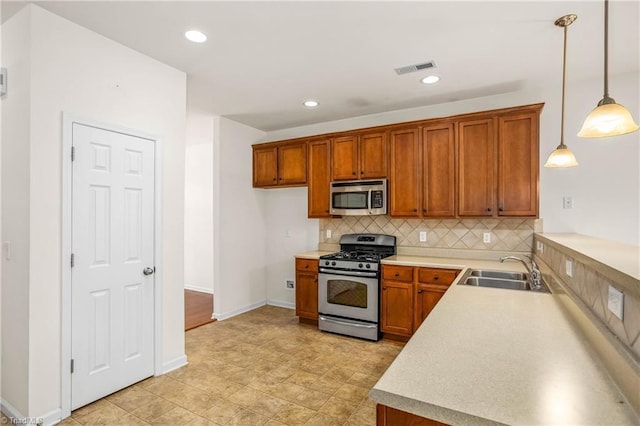 kitchen featuring brown cabinets, a sink, appliances with stainless steel finishes, and decorative backsplash
