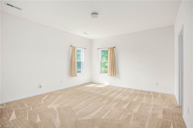 spare room featuring visible vents, light carpet, and baseboards