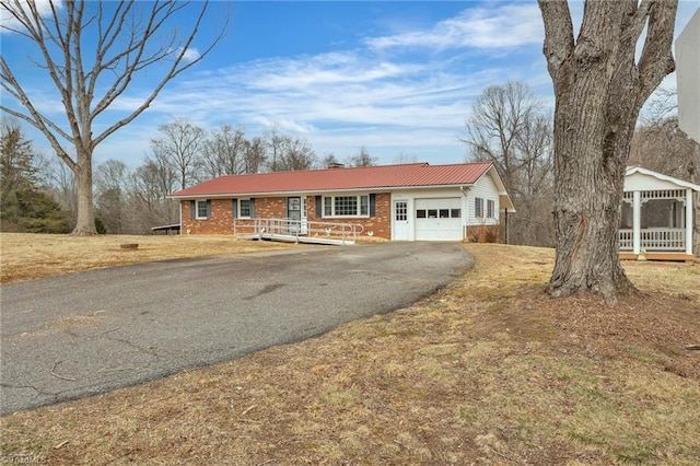 ranch-style home with a garage, aphalt driveway, and brick siding