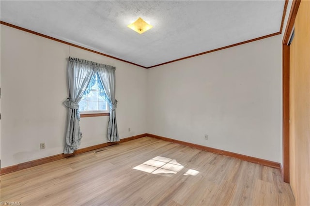 spare room with ornamental molding, light wood-style flooring, and baseboards