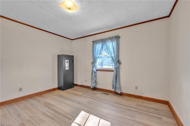 unfurnished room with crown molding, light wood-style flooring, and baseboards