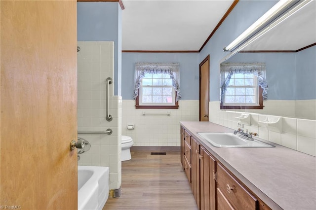 full bath featuring ornamental molding, a healthy amount of sunlight, tile walls, and vanity