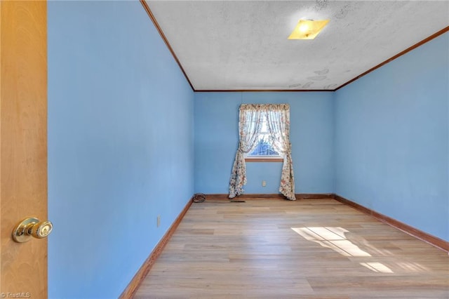 spare room featuring crown molding, baseboards, and wood finished floors