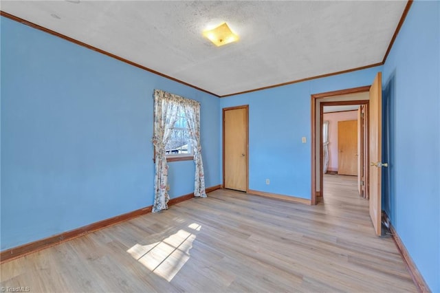 empty room featuring ornamental molding, light wood-style flooring, and baseboards