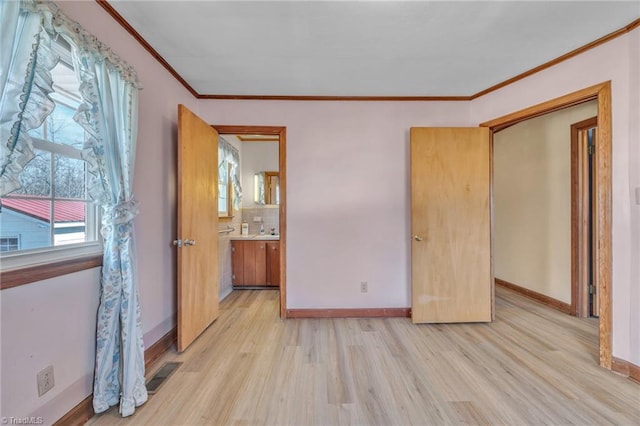 unfurnished bedroom with ornamental molding, visible vents, light wood-style floors, and baseboards