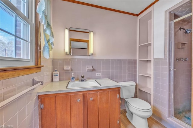 full bath with toilet, vanity, tile walls, a stall shower, and crown molding