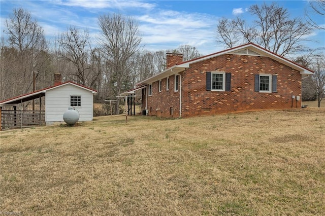 view of side of home featuring brick siding, a chimney, and a yard