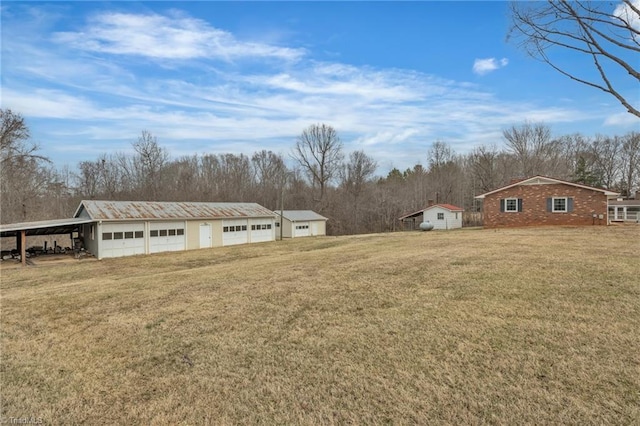 view of yard featuring an outbuilding, a detached garage, and driveway