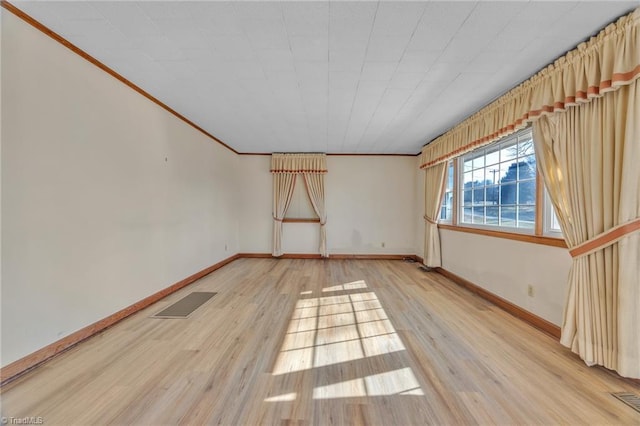 unfurnished room featuring light wood-type flooring, baseboards, visible vents, and crown molding