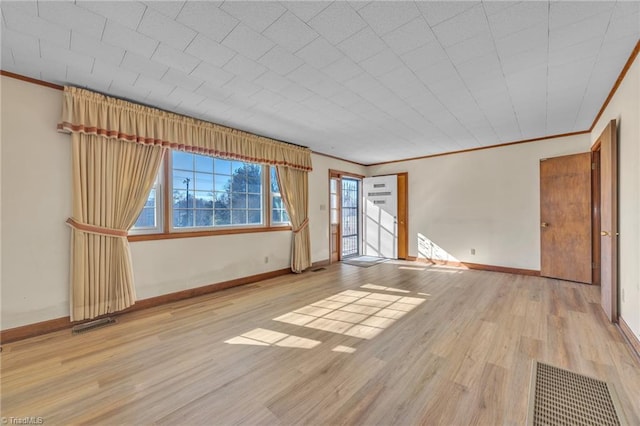 spare room with baseboards, visible vents, wood finished floors, and ornamental molding