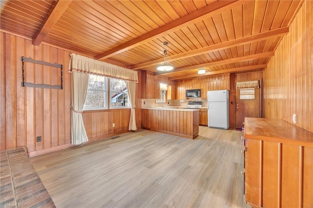 kitchen featuring brown cabinetry, beamed ceiling, freestanding refrigerator, a peninsula, and light wood-style floors