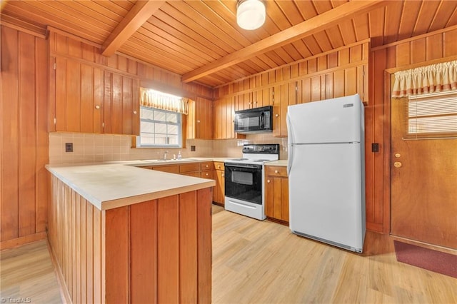 kitchen with electric range oven, freestanding refrigerator, black microwave, beamed ceiling, and a peninsula