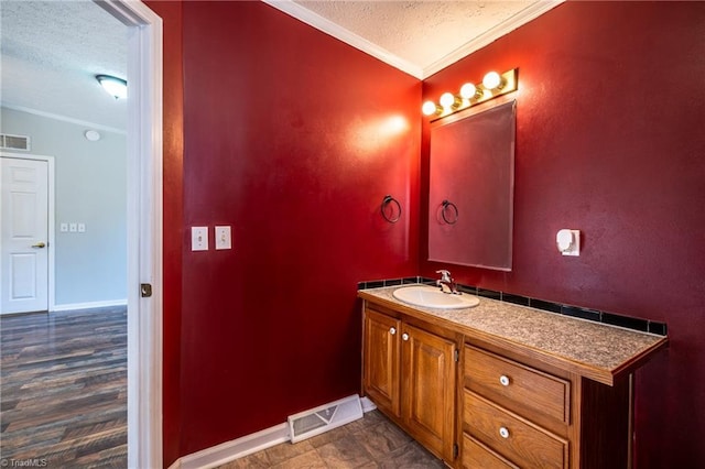 bathroom with vanity, ornamental molding, visible vents, and a textured ceiling